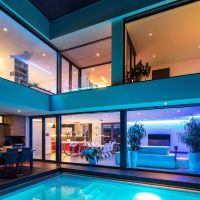 Linear and recessed fixtures in pink and blue beautifully illuminate a home from the outside, looking in.